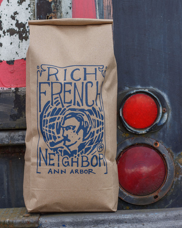 Brown paper bag with 'Rich French Neighbor' branding on a textured background