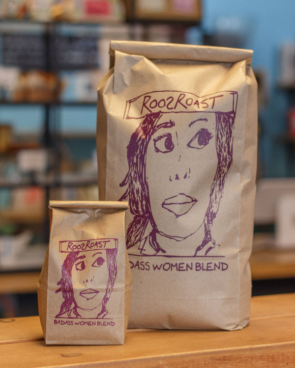 Two brown paper bags with a face illustration and 'RoozRoast' branding on a wooden surface.