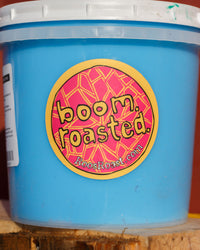 Blue bucket with a 'boom roasted' label on a wooden surface