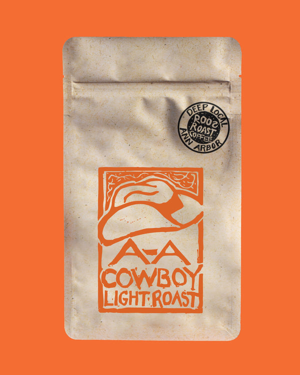 Coffee package with cowboy hat design and 'Cowboy Light Roast' text on an orange background