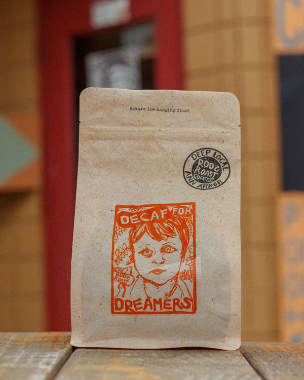 Kraft paper coffee bag with a graphic design and text on a wooden surface.