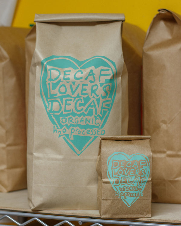 Brown paper bags with 'Decaf Lovers' logo on a yellow background