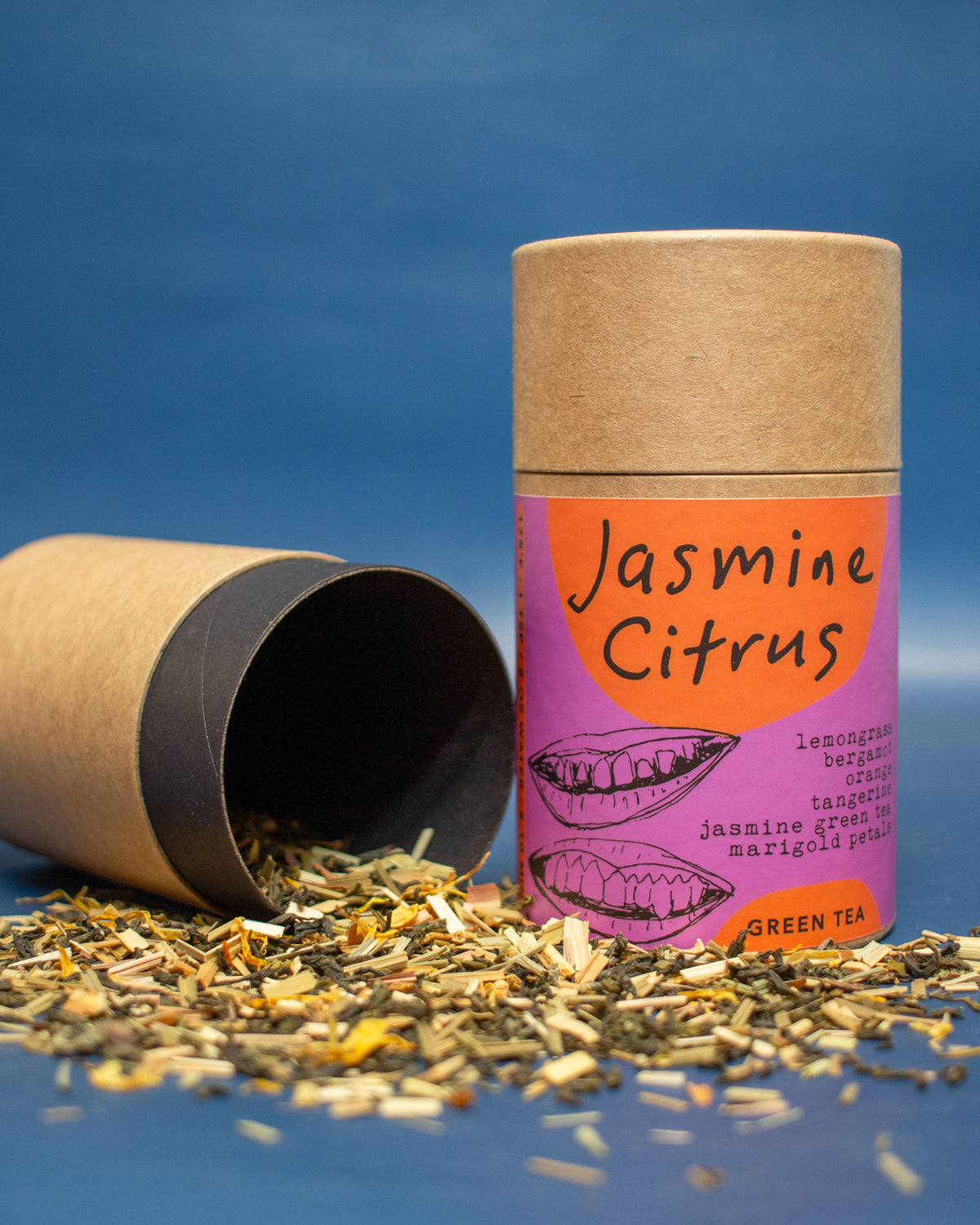 Jasmine Citrus green tea packaging with loose tea leaves on a blue background