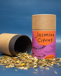 Jasmine Citrus green tea packaging with loose tea leaves on a blue background