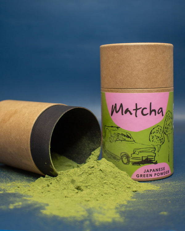 Matcha green powder in a cardboard container with a blue background
