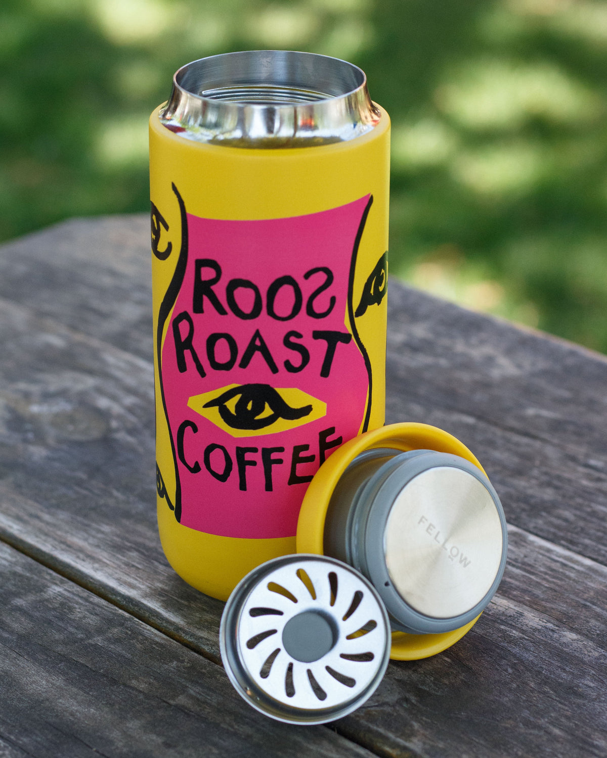 Yellow can cooler with 'Roo Roast Coffee' design on a wooden surface