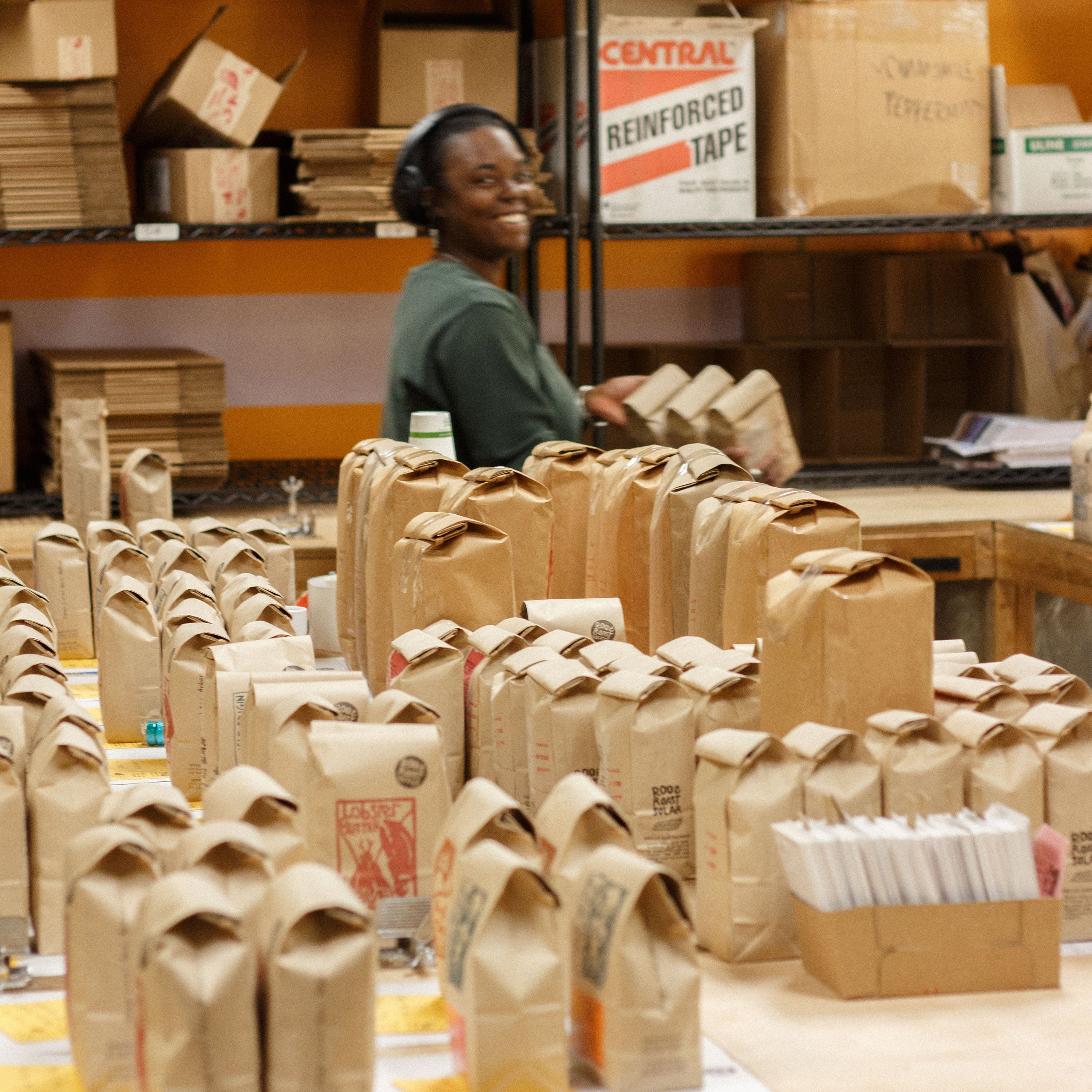 Person working in a warehouse with cardboard boxes and bags.