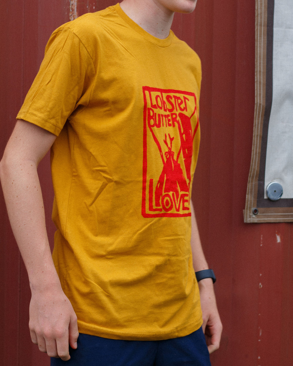 Person wearing a yellow t-shirt with red graphic design against a red background
